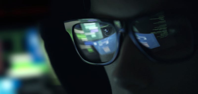 Der Ausschnitt eines Gesichtes mit Brille gehüllt in eine Kapuze