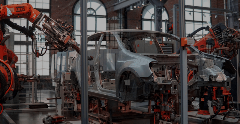 Ein Ausschnitt einer Automobilproduktion, bei dem eine Karosserie von Roboterarmen bearbeitet wird