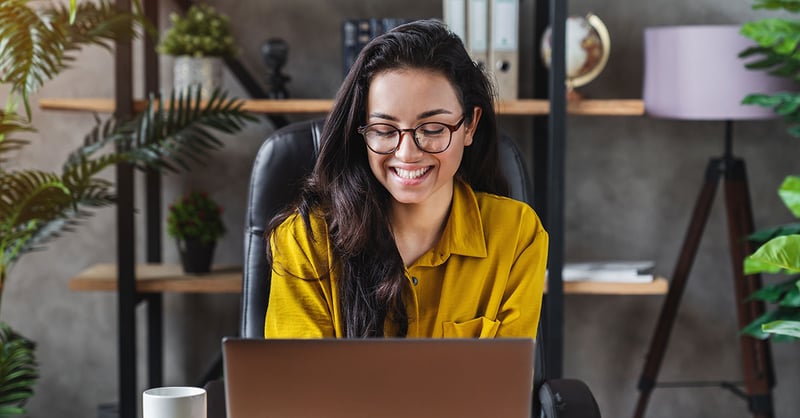Eine Frau lächelt vor einem Laptop