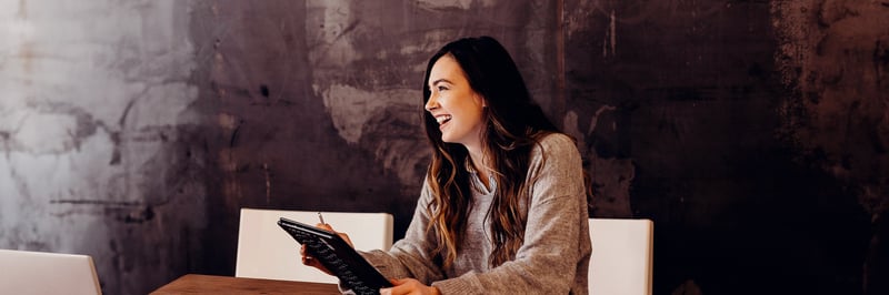 Eine junge Frau arbeitet an einem Laptop und lacht