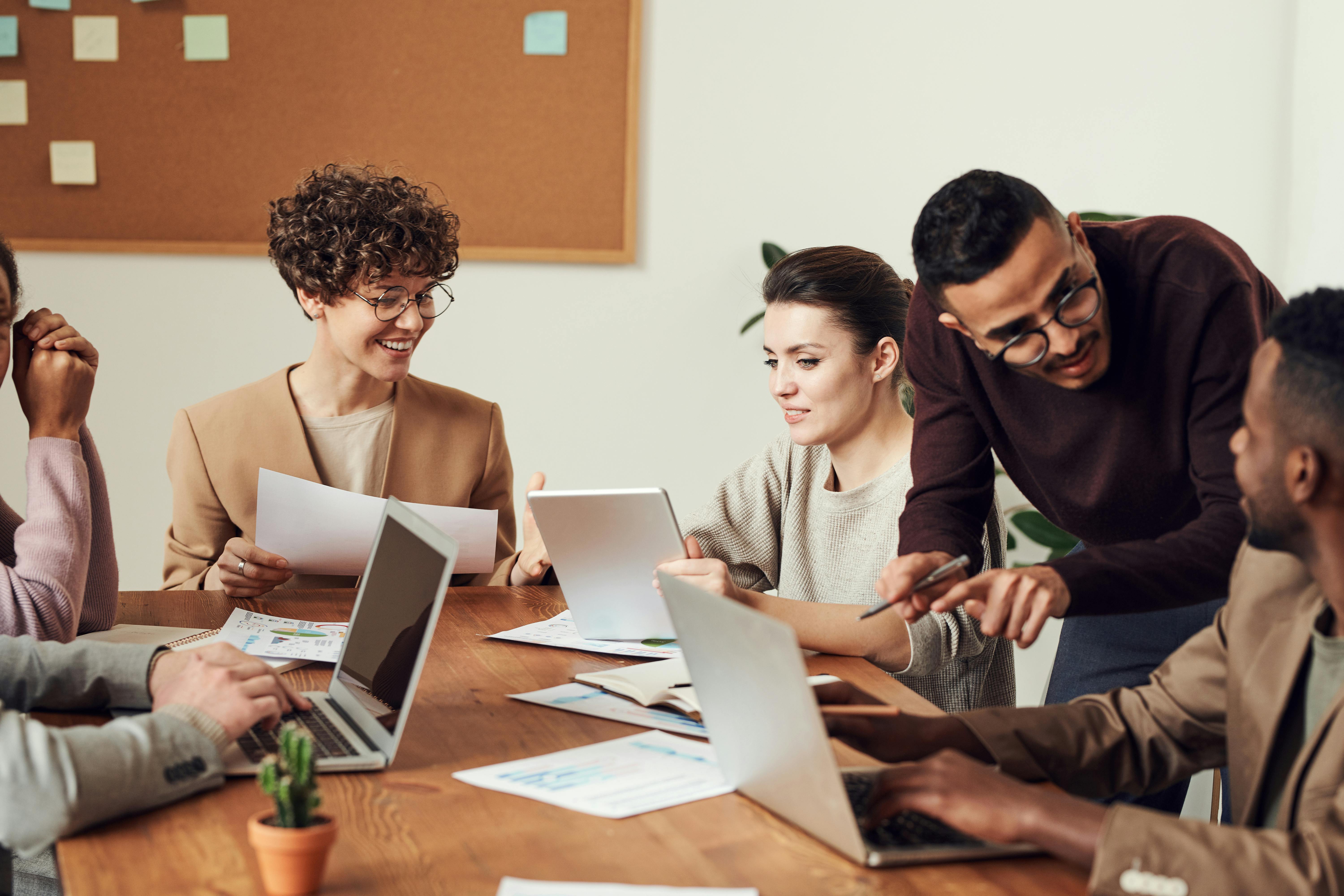 Frauen und Mann in einem Meeting mit Laptops