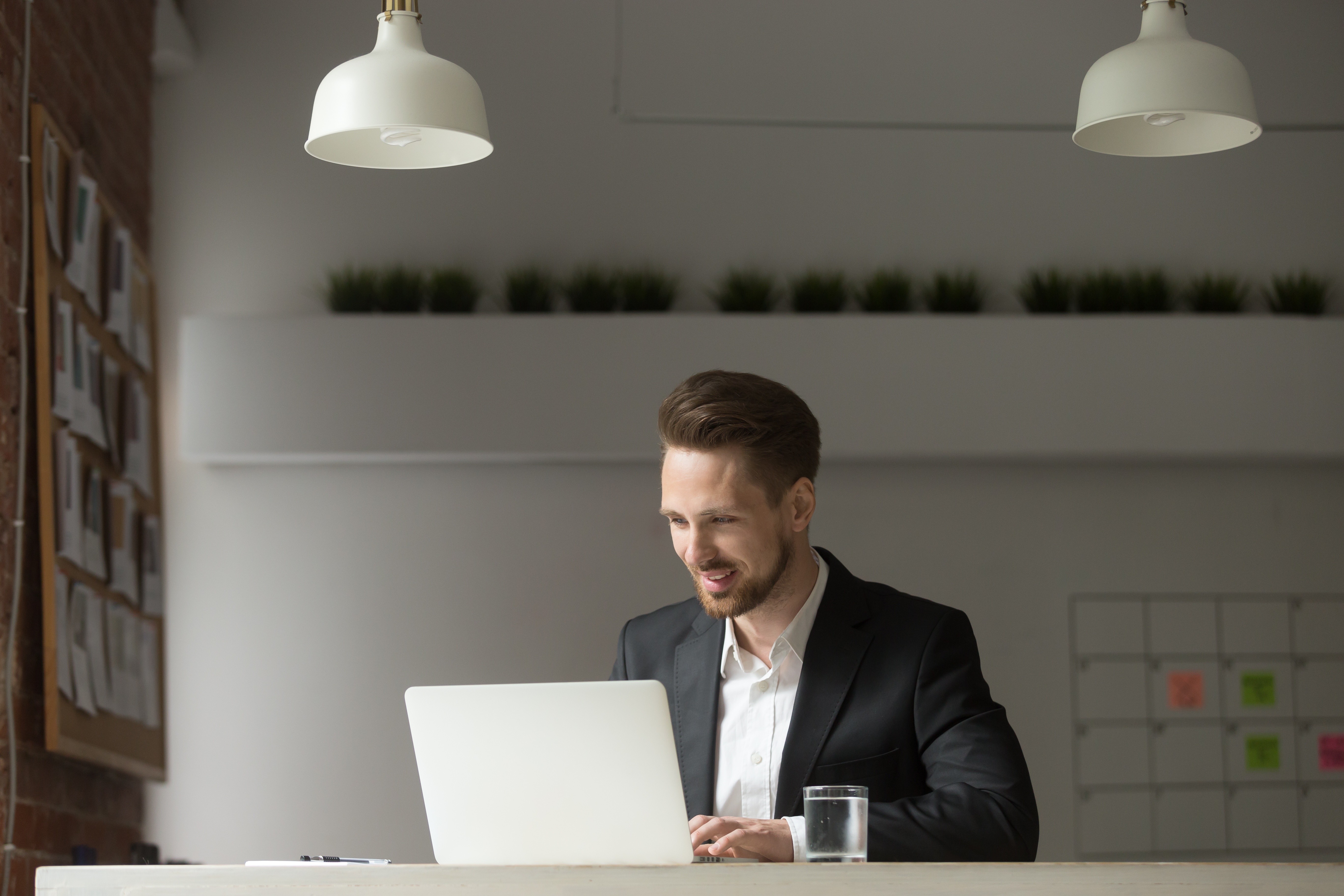 Mann sitzt mit Laptop und arbeitet